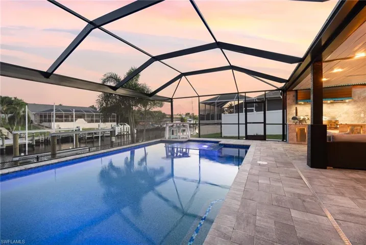 Pool at dusk featuring a lanai and a patio area
