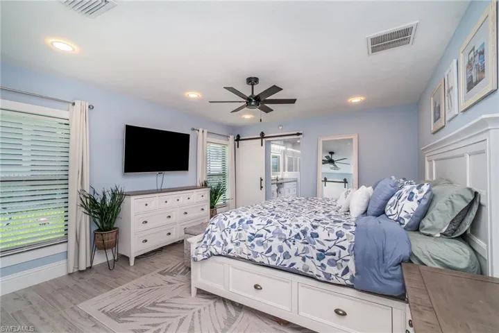 Owners bedroom featuring tile plank floors, walk in closet, ensuite bathroom, a barn door.