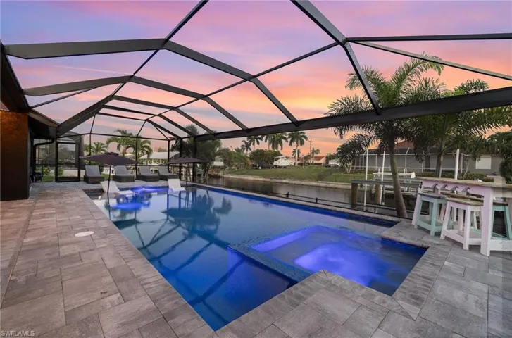 Pool at dusk featuring screened enclosure