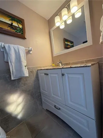 Bathroom with tile patterned floors, vanity, and tile walls