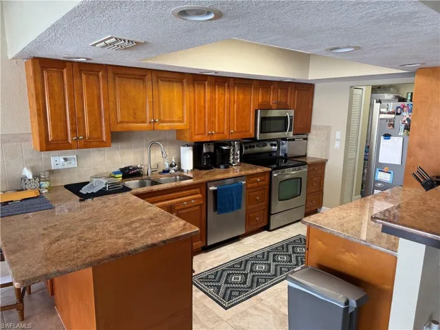 Kitchen featuring sink, a breakfast bar area, stainless steel appliances, tasteful backsplash, and kitchen peninsula