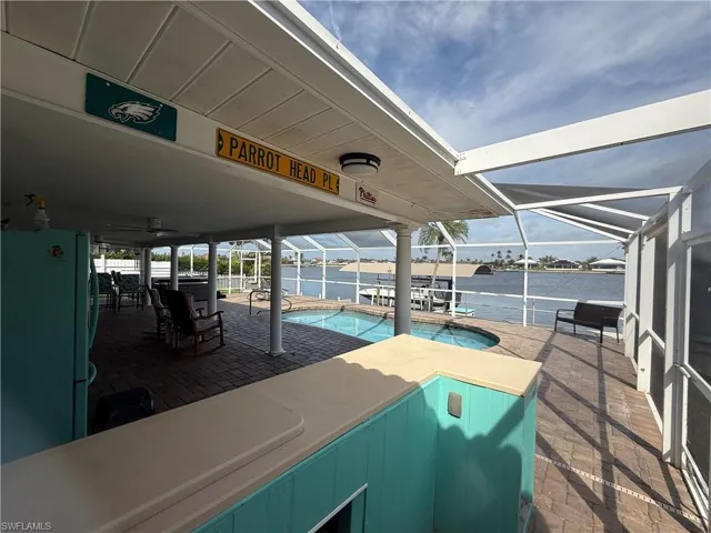 View of patio with ceiling fan, a water view, and glass enclosure