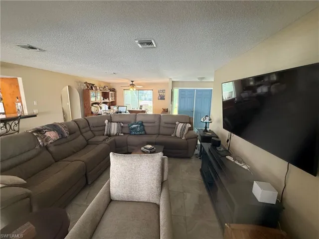 Living room with ceiling fan and a textured ceiling