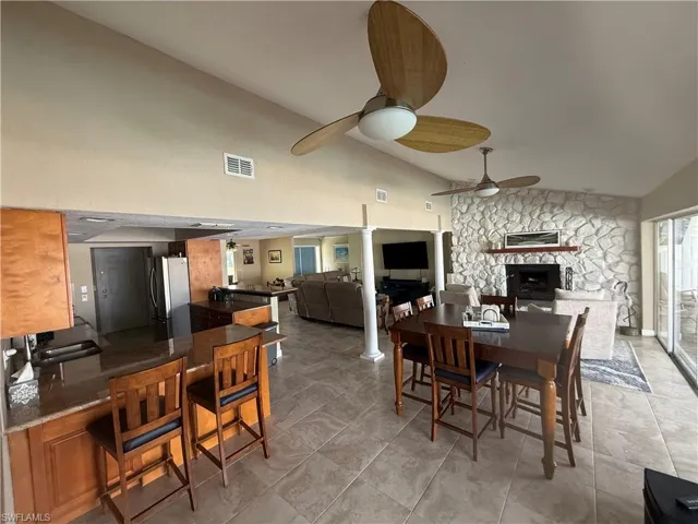 Dining space featuring a ceiling fan, visible vents, a fireplace, and ornate columns