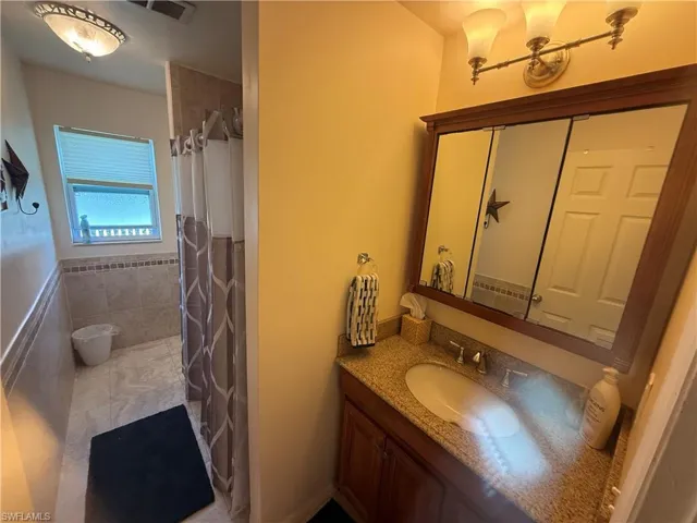 Bathroom featuring vanity, tile walls, tile patterned floors, and walk in shower