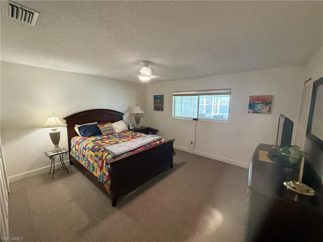 Bedroom featuring carpet, a textured ceiling, and ceiling fan