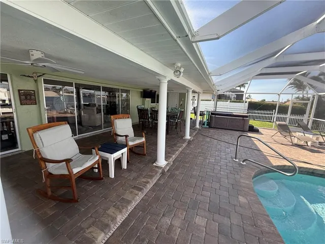 View of patio / terrace featuring a hot tub, a fenced in pool, ceiling fan, a lanai, and fence