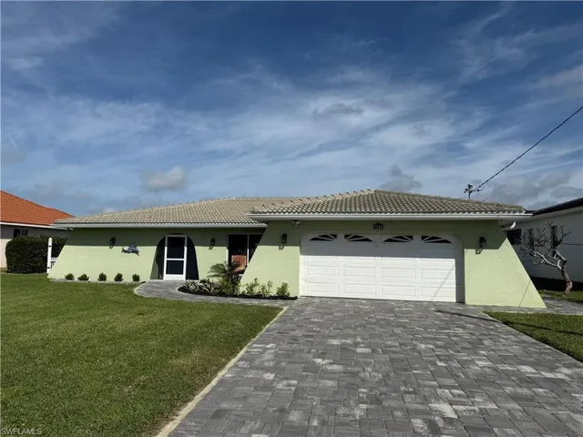 View of front facade featuring a garage and a front lawn