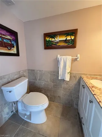 Bathroom featuring vanity, tile walls, tile patterned floors, and toilet