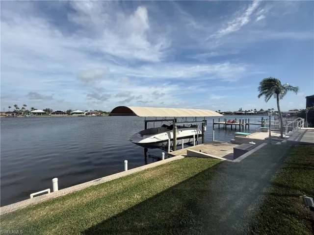 Dock area with a water view and a lawn