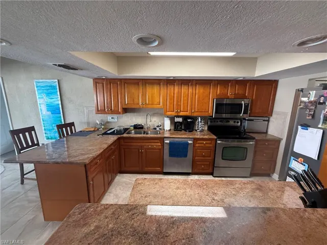 Kitchen featuring sink, stainless steel appliances, kitchen peninsula, and a textured ceiling