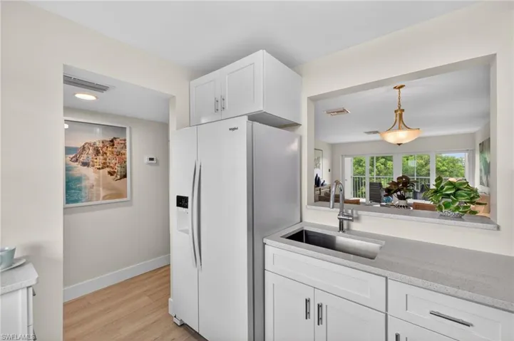 Kitchen with quartz countertops, white appliances and pass through window