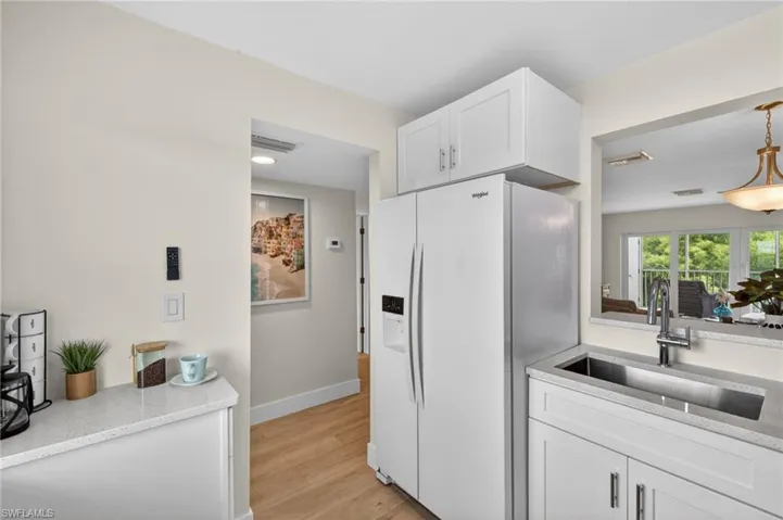 Kitchen with quartz countertops, white appliances and pass through window