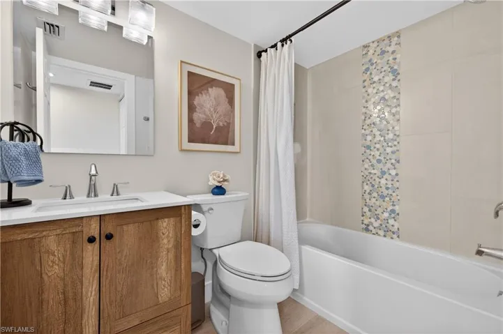 Full Guest Bathroom with decorative accent tile, coastal vanity and upscale lighting.