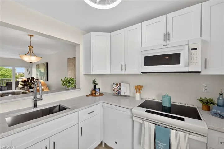 Kitchen with quartz countertops, ceiling fan,  white appliances and pass through window