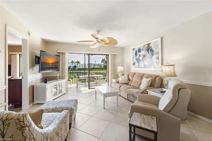 Living area featuring tile patterned flooring, ceiling fan, wainscoting, and radiator