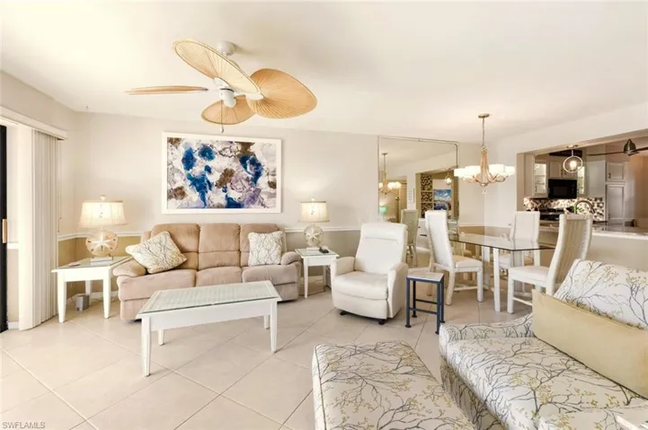 Living area with a chandelier, light tile patterned flooring, and ceiling fan