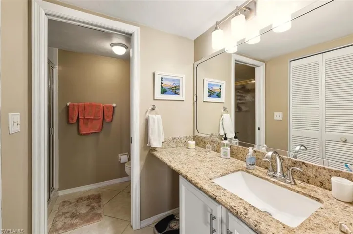 Full bathroom featuring a stall shower, vanity, a closet, and light tile patterned floors