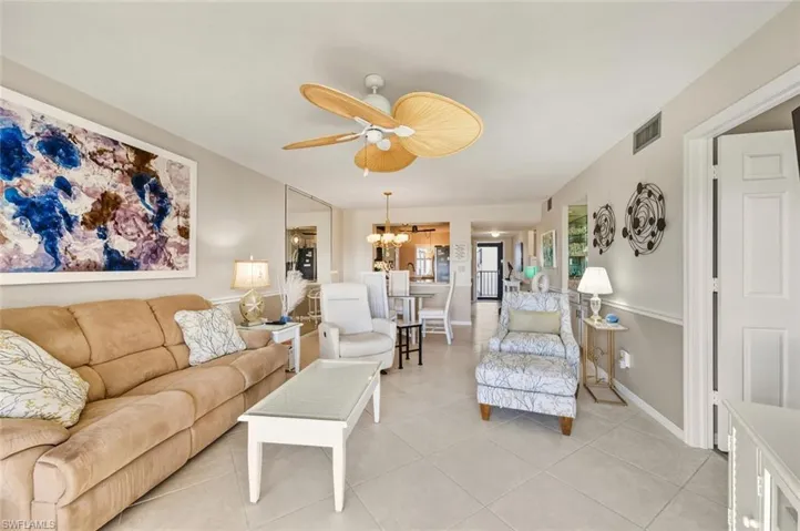 Living room featuring a ceiling fan, a chandelier, and light tile patterned flooring