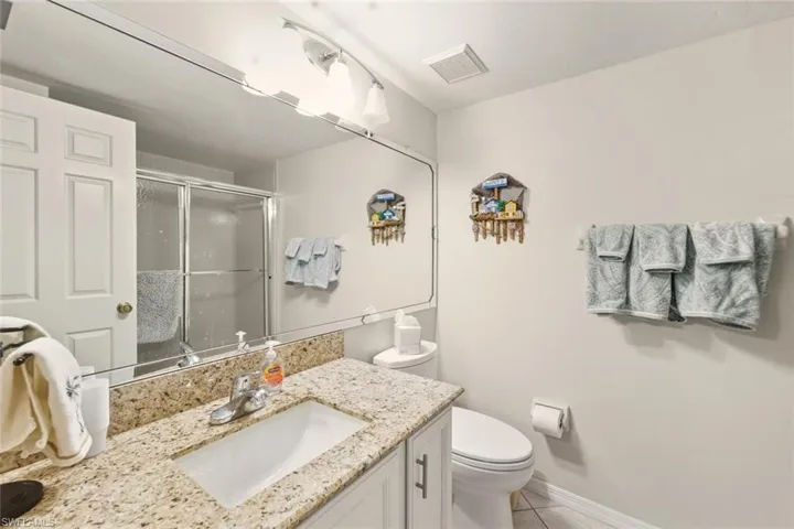 Full bathroom with a stall shower, vanity, and light tile patterned floors