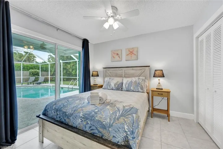 Bedroom with a sunroom, light tile patterned flooring, a closet, a ceiling fan, and access to exterior
