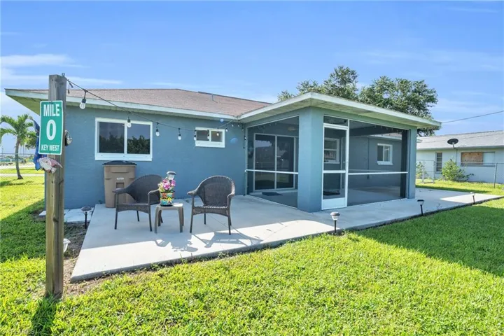 Rear view of house with a sunroom, a lawn, and a patio area