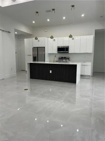 Kitchen featuring modern cabinets, refrigerator, white cabinetry, recessed lighting, and an island with sink