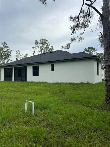 View of side of property with stucco siding and roof with shingles