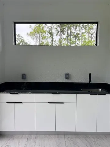 Bathroom with healthy amount of natural light, double vanity, and marble look tile flooring