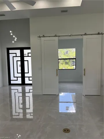 Spare room featuring marble tiled floors, a barn door, and ceiling fan