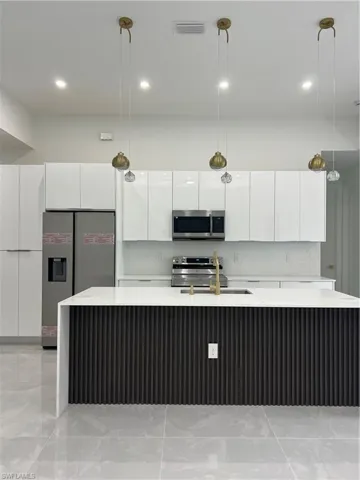 Kitchen with modern cabinets, refrigerator, light countertops, and recessed lighting