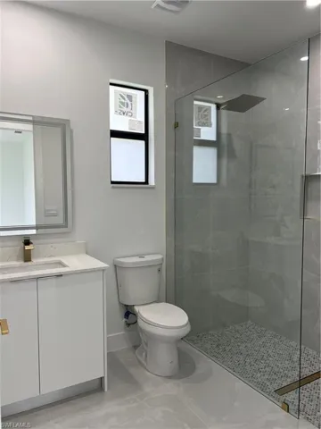 Bathroom featuring vanity, tiled shower, and marble finish flooring