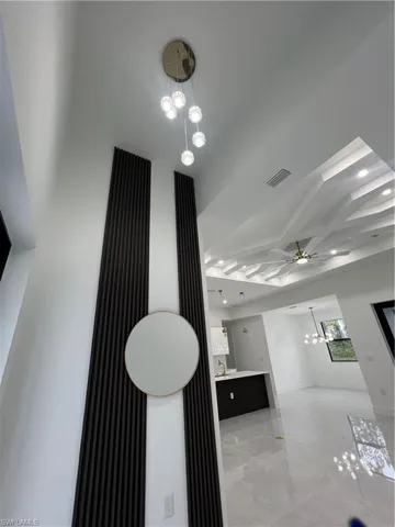 Corridor featuring a chandelier, light marble finish flooring, and recessed lighting