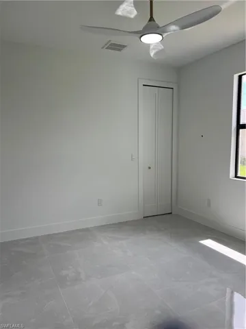 Unfurnished bedroom with light marble finish floors, ceiling fan, and a closet