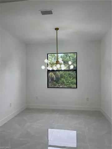 Empty room with a chandelier and light marble finish floors