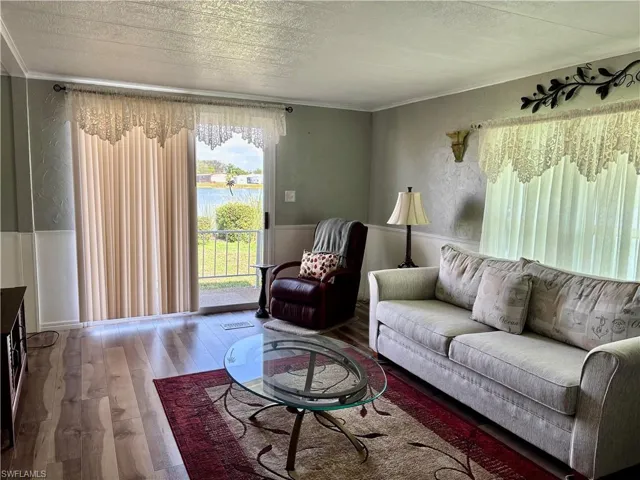 Living room featuring ornamental molding, wood-type flooring, and a textured ceiling