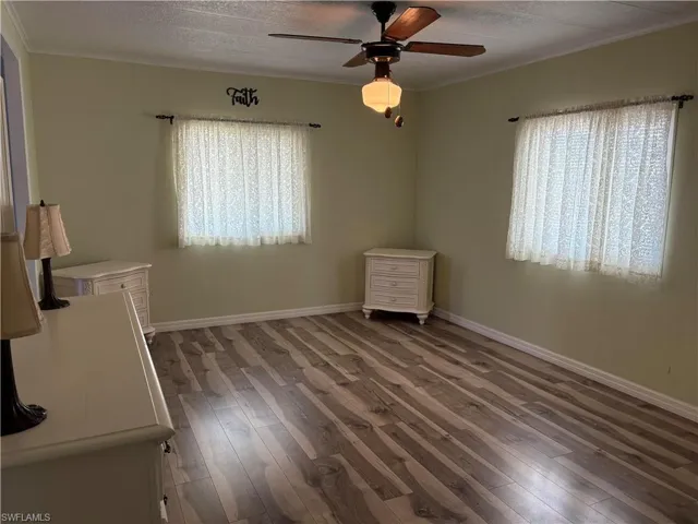 Unfurnished room with crown molding, ceiling fan, dark hardwood / wood-style floors, and a textured ceiling
