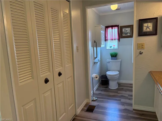 Bathroom featuring hardwood / wood-style floors, crown molding, and toilet