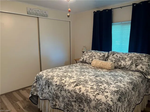 Bedroom featuring hardwood / wood-style floors, ornamental molding, and a closet