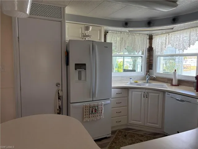Kitchen featuring sink, white appliances, and white cabinets