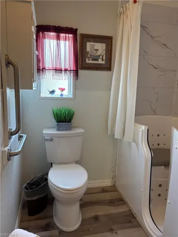 Bathroom featuring wood-type flooring, plus walk in shower, and toilet