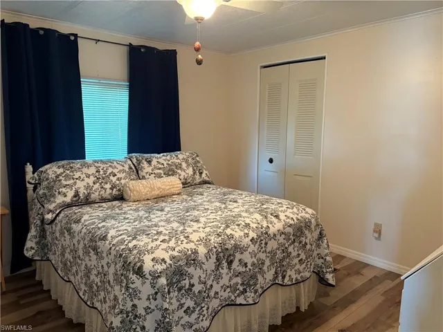 Bedroom featuring hardwood / wood-style flooring, crown molding, and a closet
