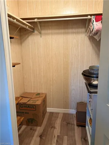 Walk in closet with hardwood / wood-style floors