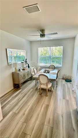 Bright interior space featuring wood-finish flooring, a contemporary ceiling fan, and large windows providing natural illumination