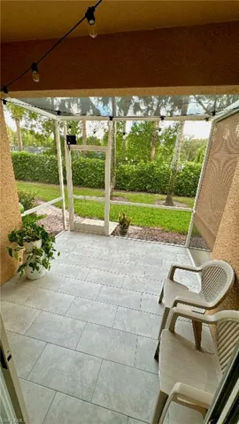 Screened patio featuring light-toned rectangular floor tiles, textured exterior walls, and a private outdoor space