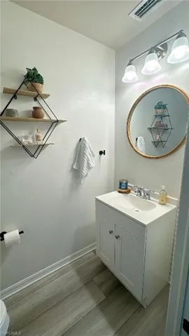 White vanity with integrated sink, chrome faucet, and mirrored cabinet