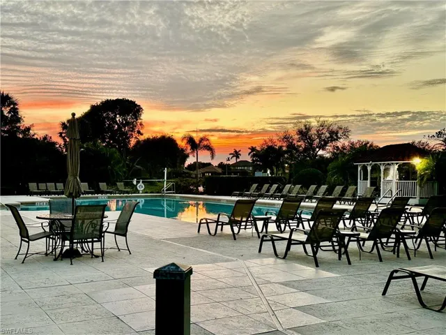 Community pool featuring a wide tiled deck, white gazebo with lighting, and extensive lounge seating