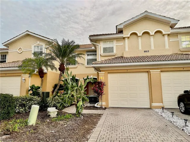 Stucco exterior with a tiled roof, featuring decorative arched accents and multiple windows