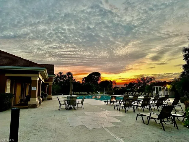 Outdoor swimming pool surrounded by a large paver patio, a white gazebo, and lush landscaping