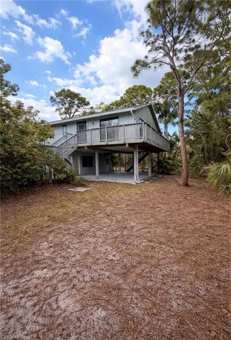 Rear view of property featuring a wooden deck, a patio, and a carport